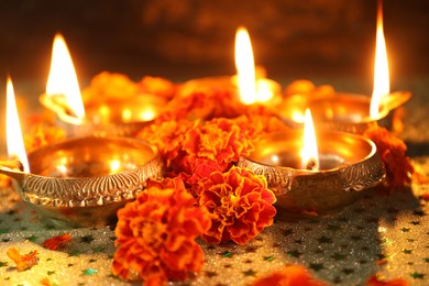 Photo of Diwali celebration. Diya lamps and beautiful marigold flowers on gray patterned surface, closeup