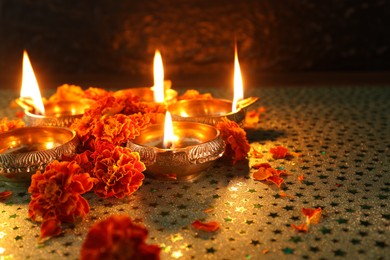 Diwali celebration. Diya lamps and beautiful marigold flowers on gray patterned surface, closeup