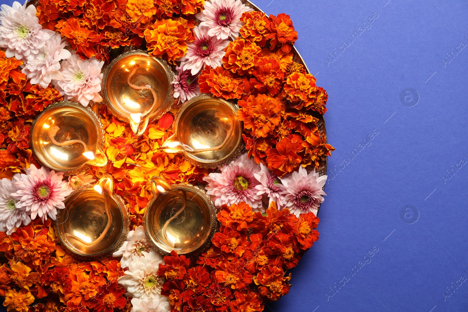 Photo of Diwali celebration. Diya lamps and beautiful flowers on blue background, top view