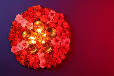 Diwali celebration. Diya lamps and beautiful flowers on color background, top view. Space for text