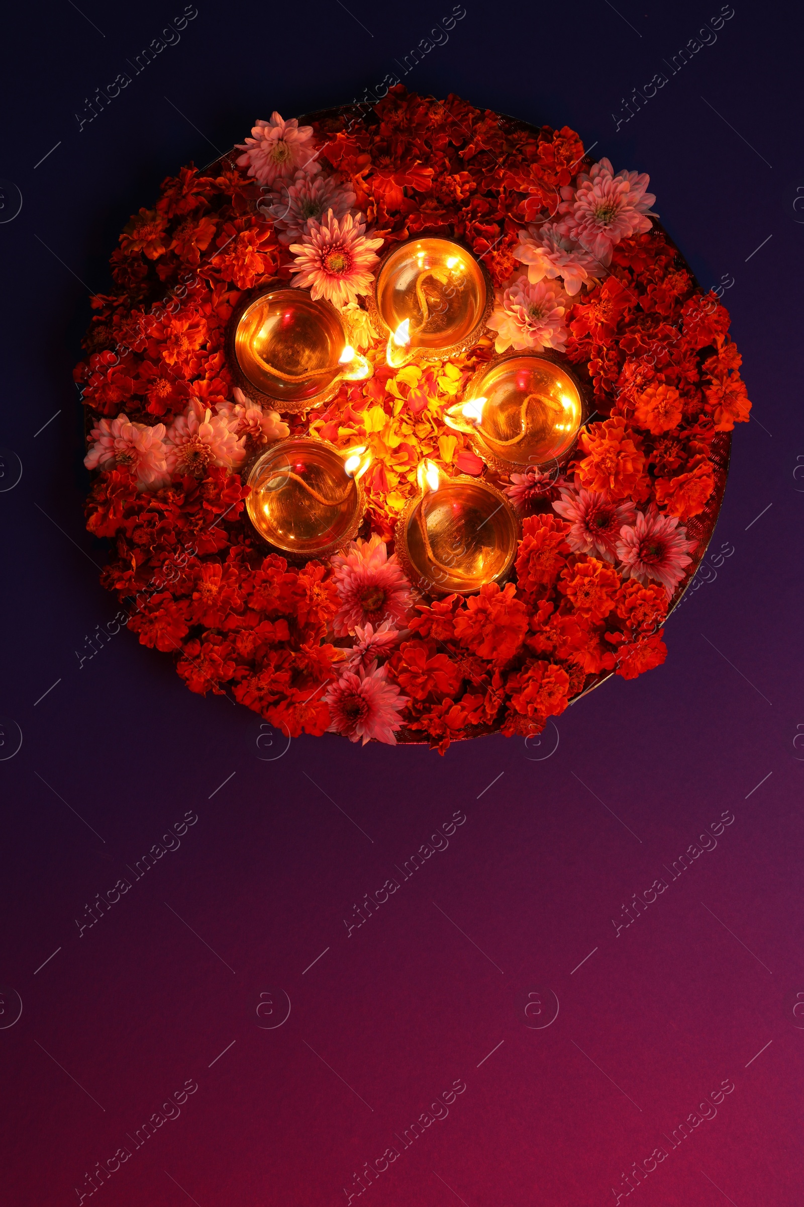 Photo of Diwali celebration. Diya lamps and beautiful flowers on color background, top view. Space for text