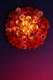 Photo of Diwali celebration. Diya lamps and beautiful flowers on color background, top view. Space for text