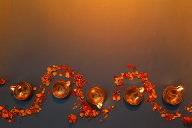 Photo of Diwali celebration. Diya lamps and beautiful flowers on color background, flat lay. Space for text