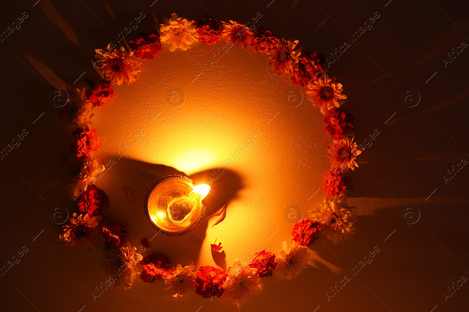 Photo of Diwali celebration. Diya lamp and beautiful flowers on dark textured surface, flat lay. Space for text