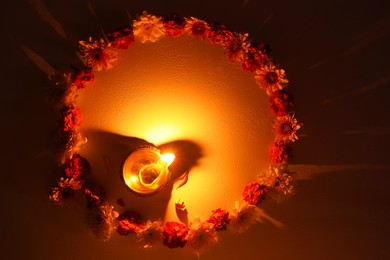 Photo of Diwali celebration. Diya lamp and beautiful flowers on dark textured surface, flat lay. Space for text