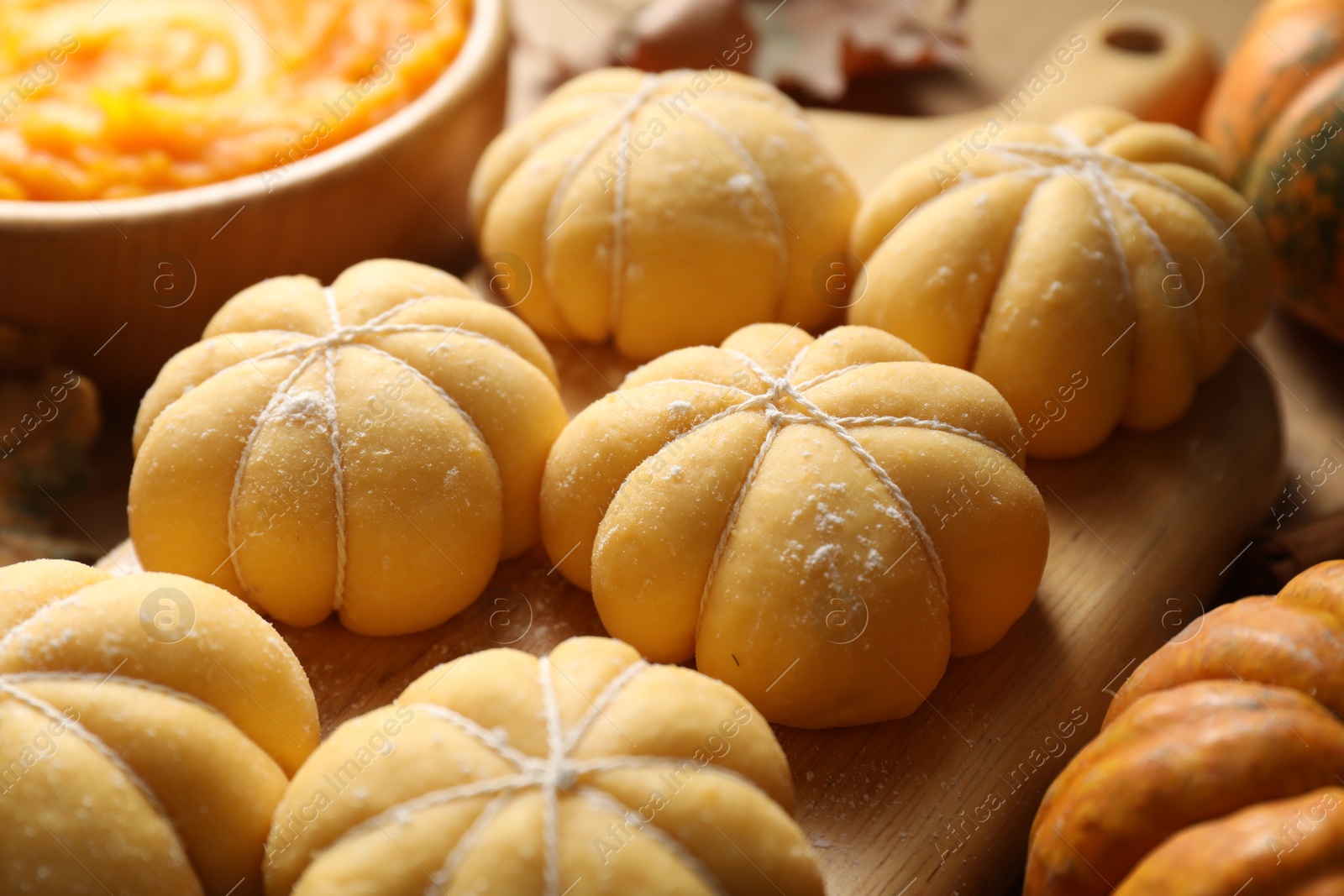 Photo of Raw pumpkin shaped buns and ingredients on table, closeup