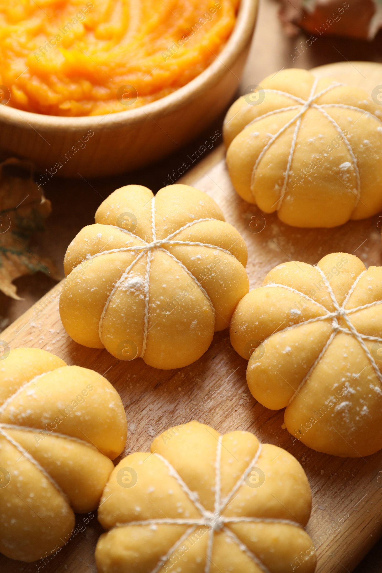 Photo of Raw pumpkin shaped buns and ingredients on table, closeup