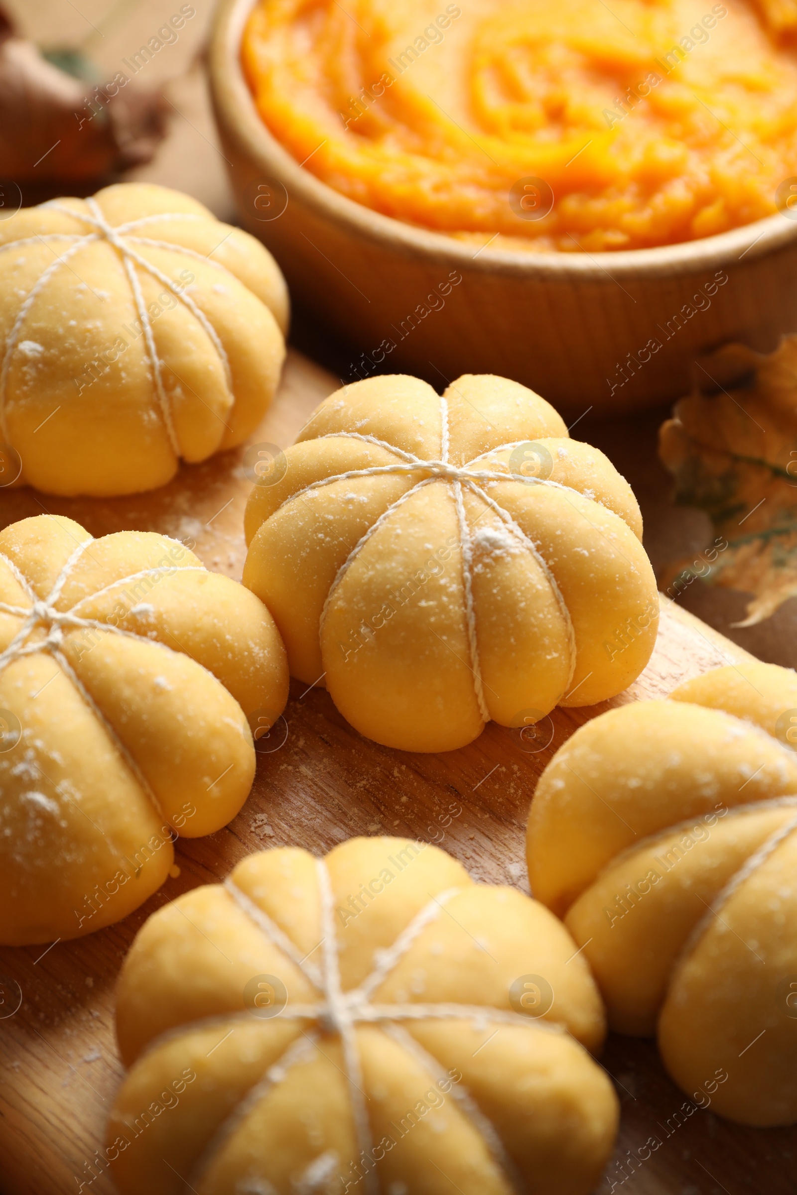 Photo of Raw pumpkin shaped buns and ingredients on table, closeup