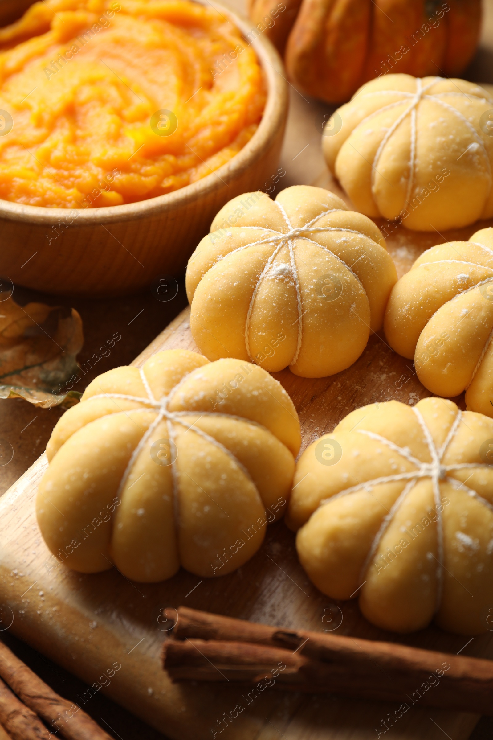 Photo of Raw pumpkin shaped buns and ingredients on table, closeup