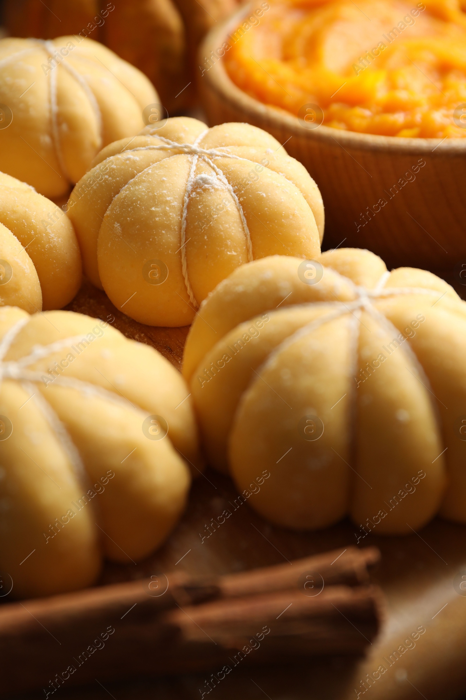 Photo of Raw pumpkin shaped buns and ingredients on table, closeup