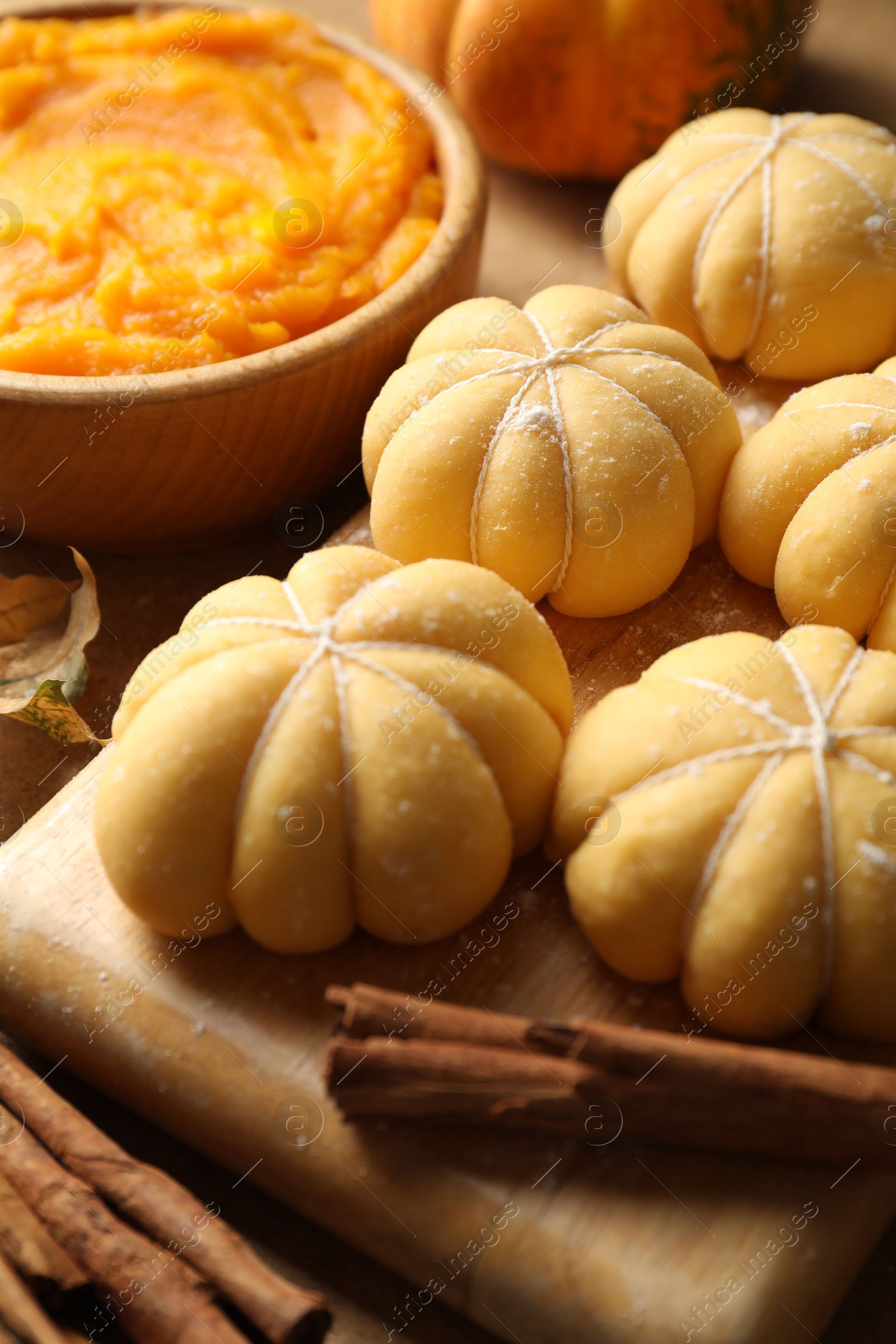 Photo of Raw pumpkin shaped buns and ingredients on table, closeup