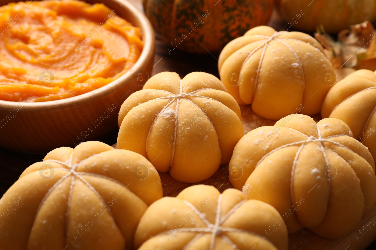 Photo of Raw pumpkin shaped buns and ingredients on table, closeup