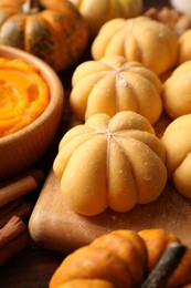 Photo of Raw pumpkin shaped buns and ingredients on wooden table, closeup