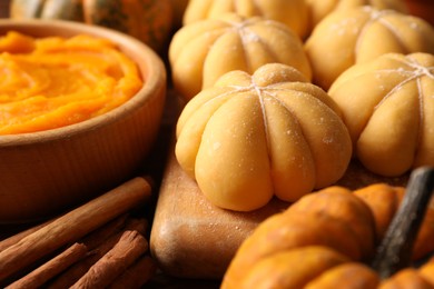 Photo of Raw pumpkin shaped buns and ingredients on wooden table, closeup