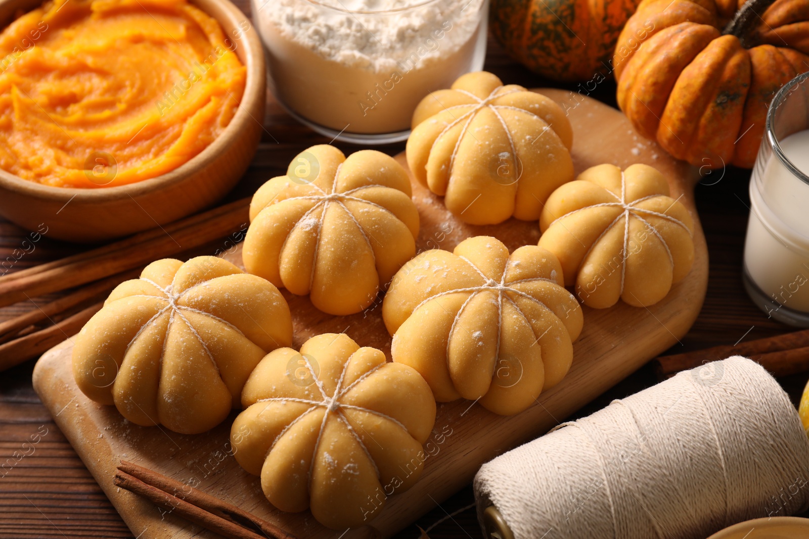 Photo of Raw pumpkin shaped buns and ingredients on wooden table