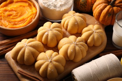 Photo of Raw pumpkin shaped buns and ingredients on wooden table