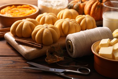 Photo of Raw pumpkin shaped buns and ingredients on wooden table