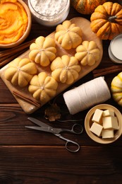 Photo of Raw pumpkin shaped buns and ingredients on wooden table, flat lay