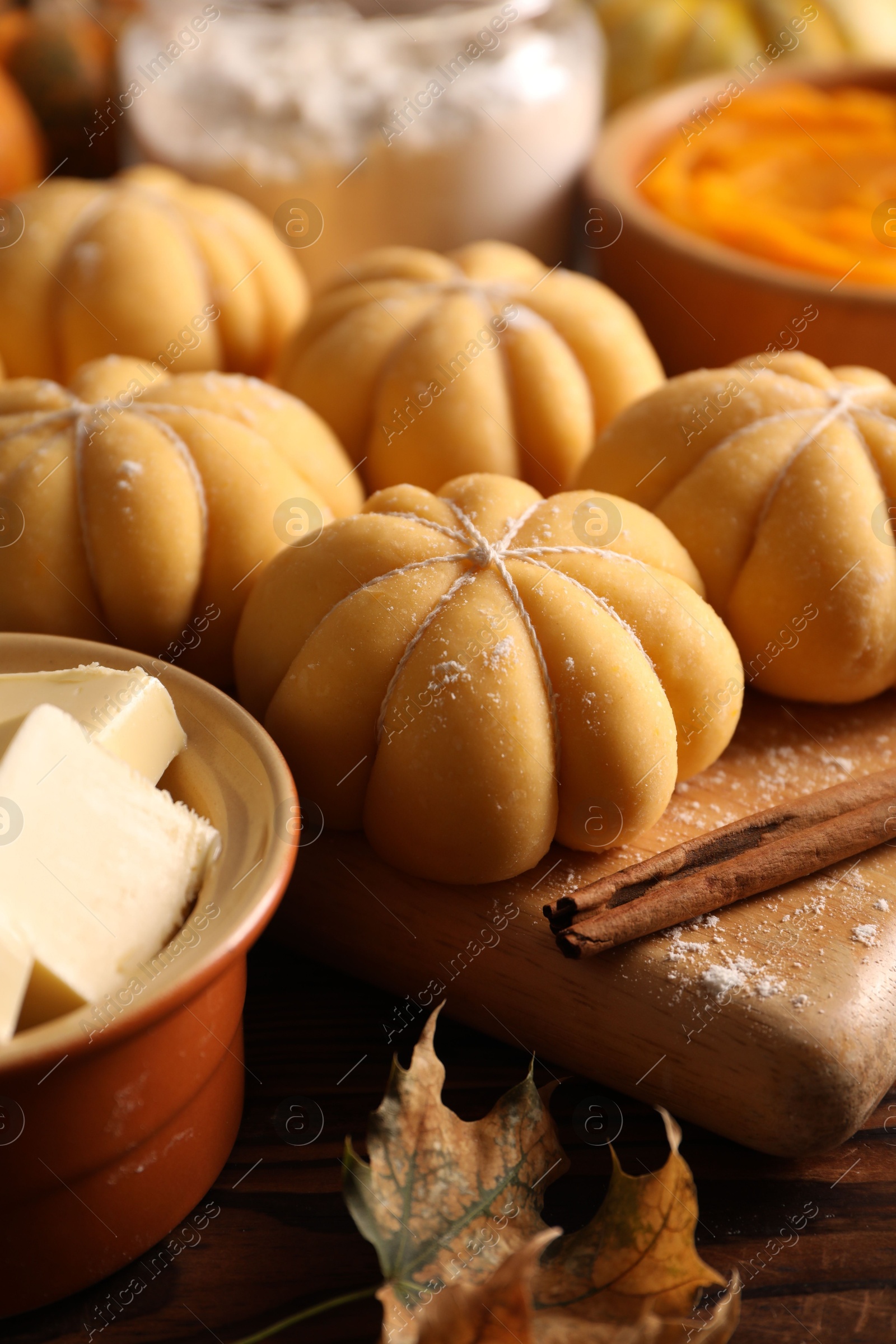 Photo of Raw pumpkin shaped buns and ingredients on wooden table, closeup