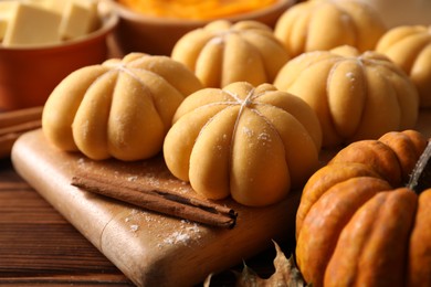 Photo of Raw pumpkin shaped buns and ingredients on wooden table, closeup