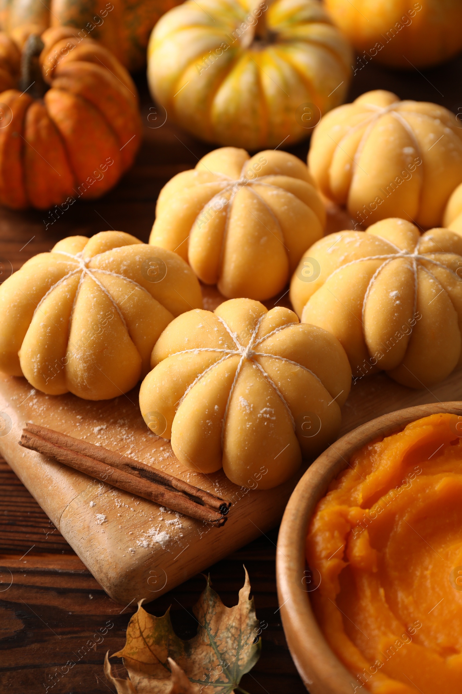 Photo of Raw pumpkin shaped buns and ingredients on wooden table, closeup