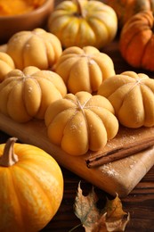 Photo of Raw pumpkin shaped buns and ingredients on wooden table, closeup