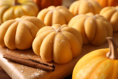 Photo of Raw pumpkin shaped buns and ingredients on wooden table, closeup