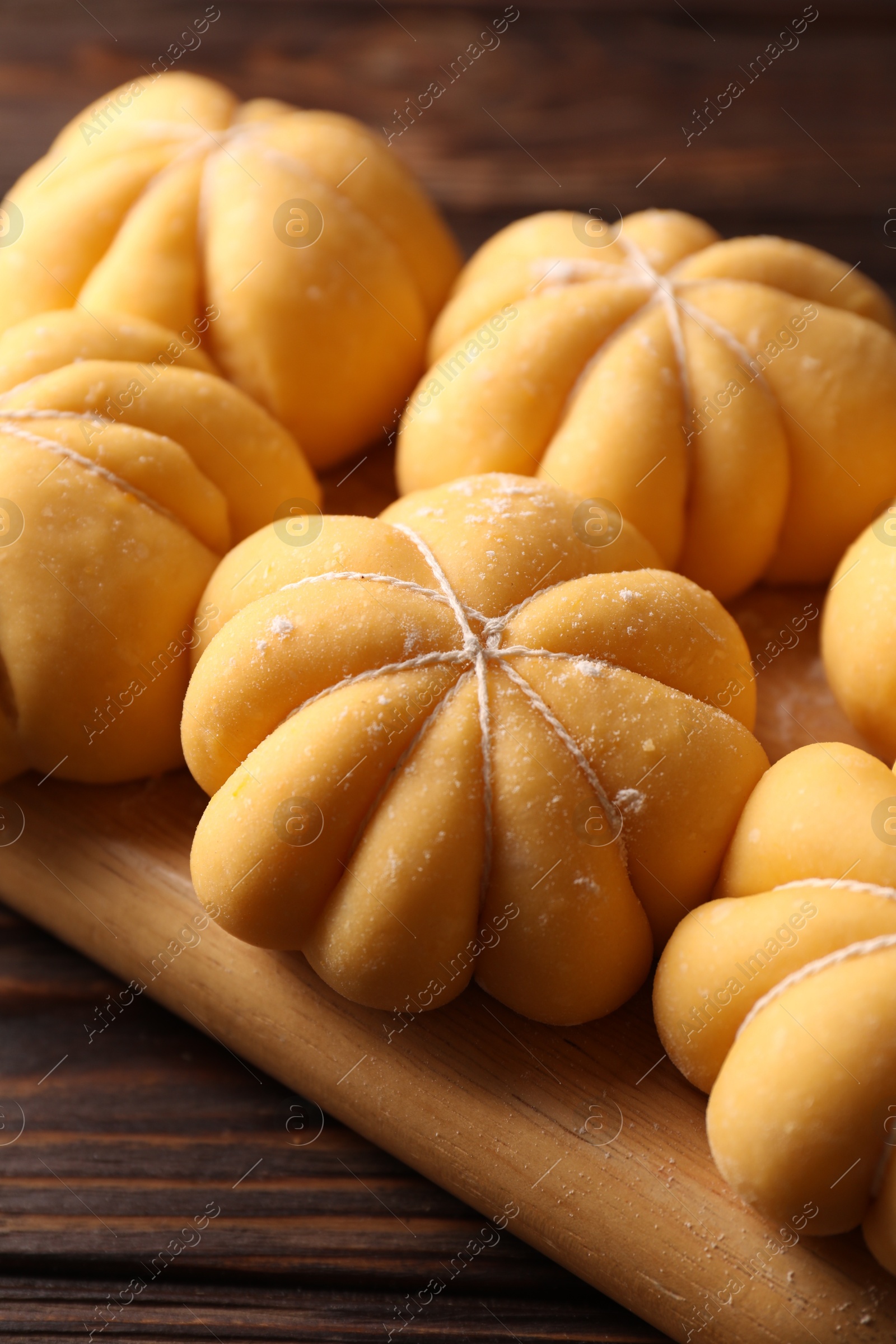 Photo of Raw pumpkin shaped buns on wooden table, closeup