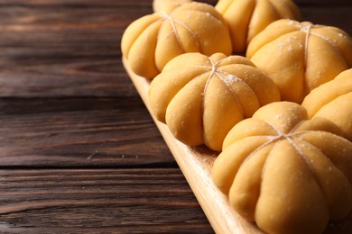 Photo of Raw pumpkin shaped buns on wooden table, closeup. Space for text