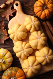 Photo of Raw pumpkin shaped buns and ingredients on wooden table, flat lay