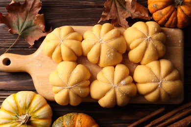 Photo of Raw pumpkin shaped buns and ingredients on wooden table, flat lay