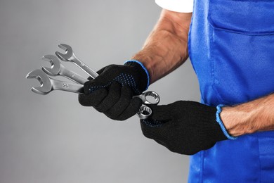 Auto mechanic with wrenches on grey background, closeup