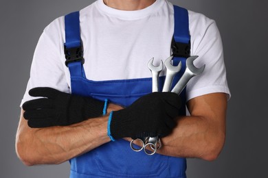 Photo of Auto mechanic with wrenches on grey background, closeup