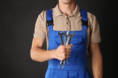 Auto mechanic with wrenches on black background, closeup. Space for text