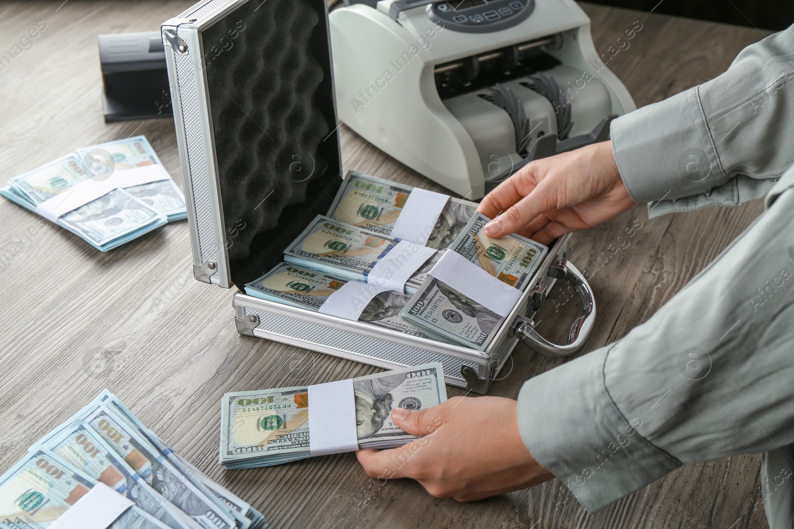 Photo of Woman counting dollar banknotes at wooden table, closeup