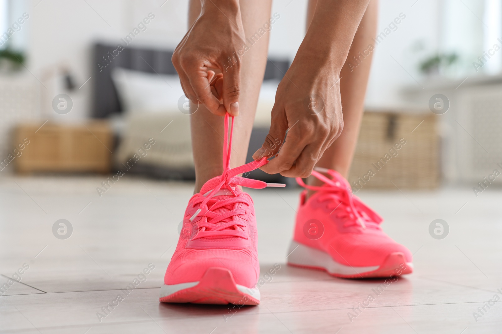 Photo of Woman tying shoelace of pink sneaker indoors, closeup. Space for text