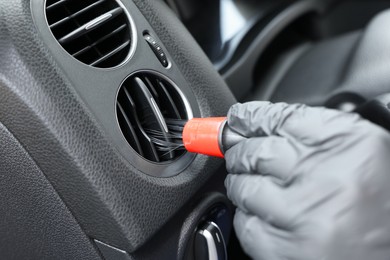 Man cleaning air vent with brush in car, closeup