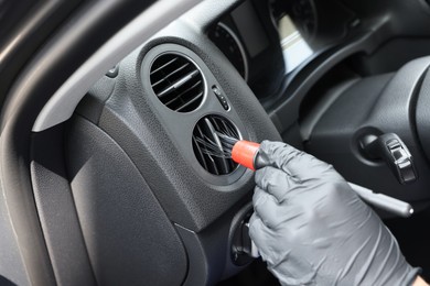 Man cleaning air vent with brush in car, closeup