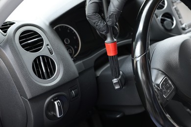 Man cleaning car interior with brush, closeup