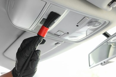 Photo of Man cleaning car interior with brush, closeup