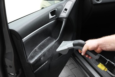 Photo of Man cleaning car door with vacuum cleaner, closeup