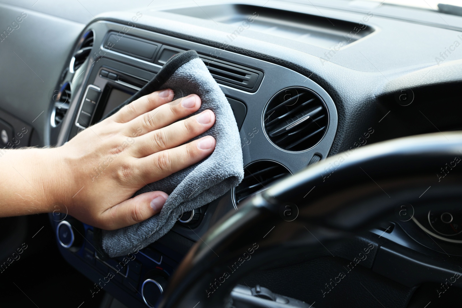 Photo of Man cleaning center console with rag, closeup