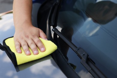 Photo of Man wiping car hood with yellow rag, closeup