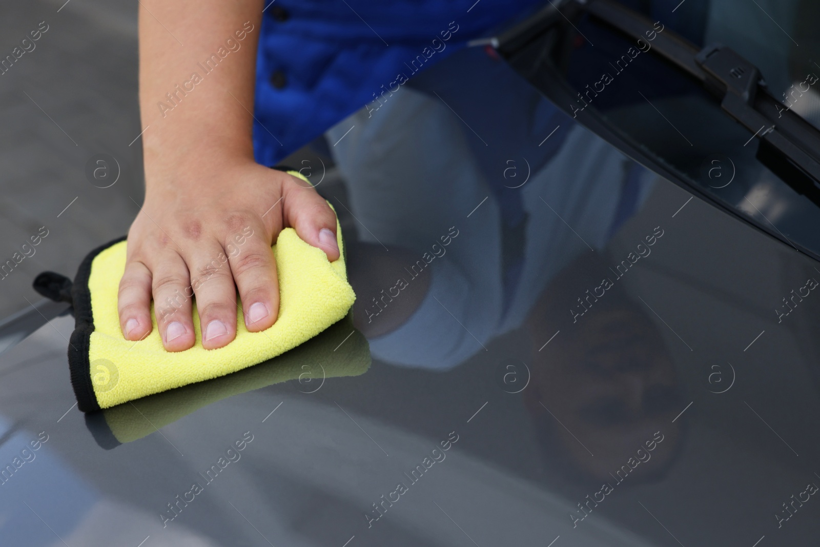 Photo of Man wiping car hood with yellow rag, closeup