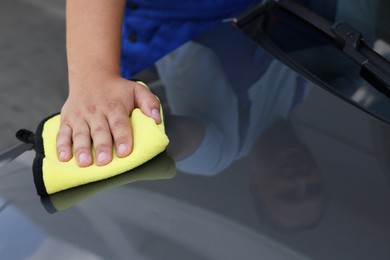 Photo of Man wiping car hood with yellow rag, closeup