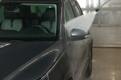 Washing auto with high pressure water jet at car wash, closeup