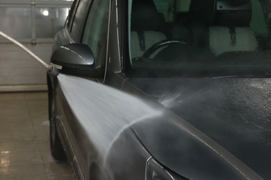 Photo of Washing auto with high pressure water jet at car wash, closeup