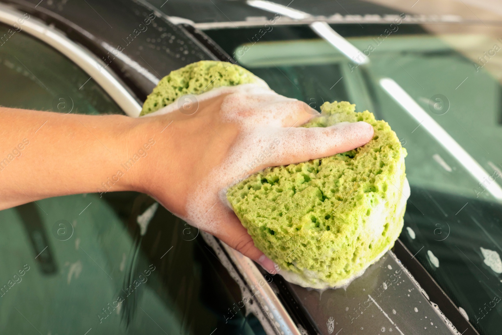 Photo of Man washing auto with sponge at car wash, closeup