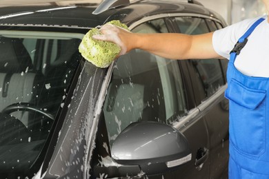 Photo of Man washing auto with sponge at car wash, closeup