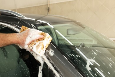 Photo of Man washing auto with sponge at car wash, closeup